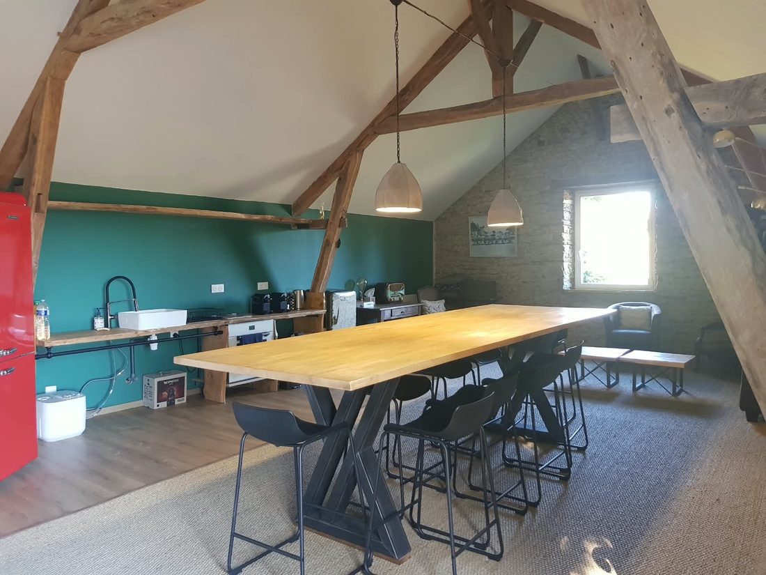 Espace cuisine et grande table sous charpente à la Maison Amarante